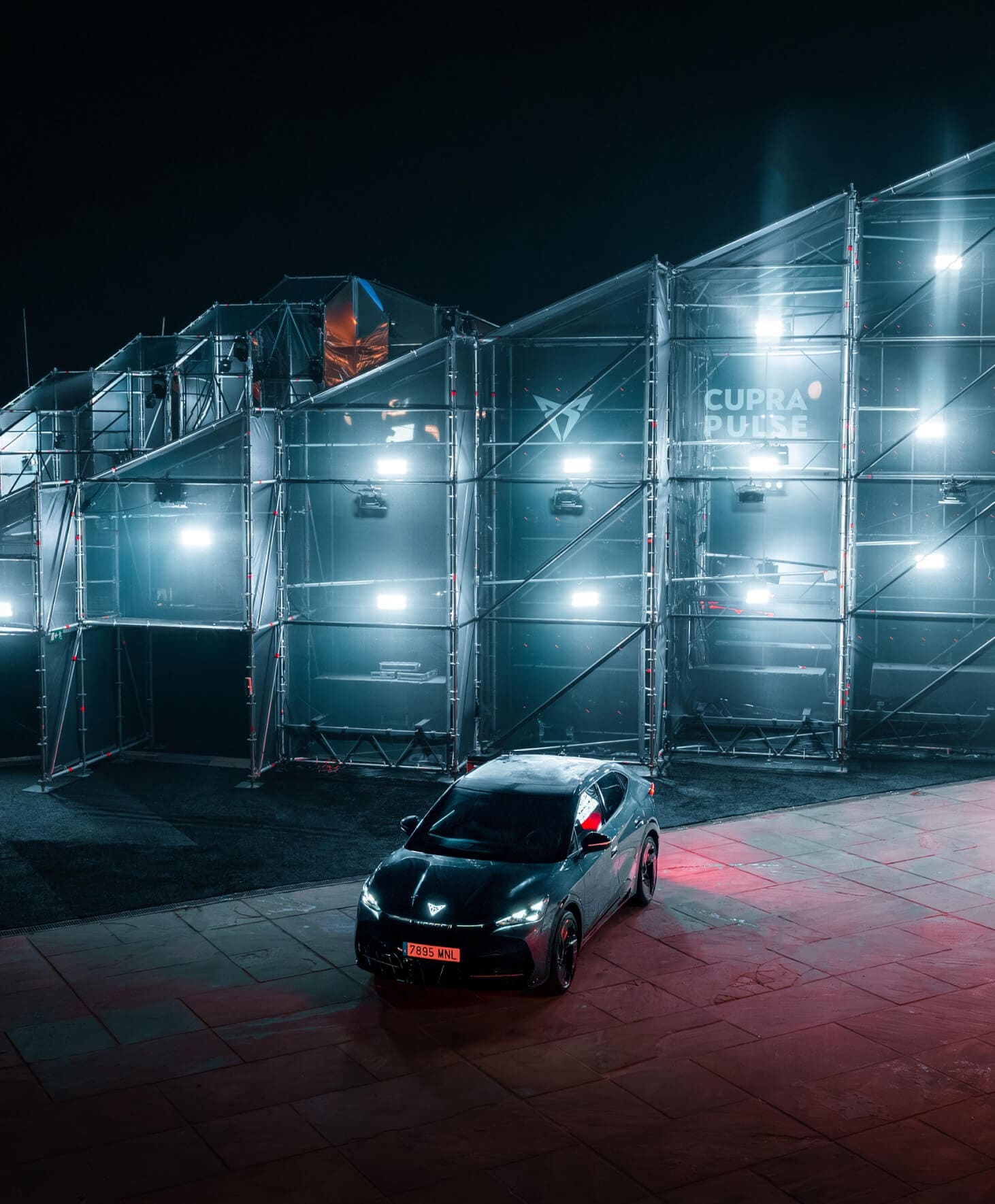A minimalist image featuring a person wearing a dark hooded garment with subtle metallic details, against a black background.